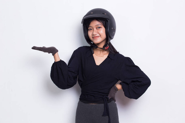 白い背景に隔絶された異なる方向に指で指すオートバイのヘルメットを身に着けている美しいアジアの女性 - 写真・画像