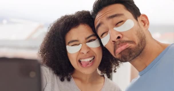 Face, beauty and selfie with a couple using an under eye mask while joking and playing with a phone in the bathroom at home. Skincare, health and humor with a man and woman having fun and recording. - Footage, Video