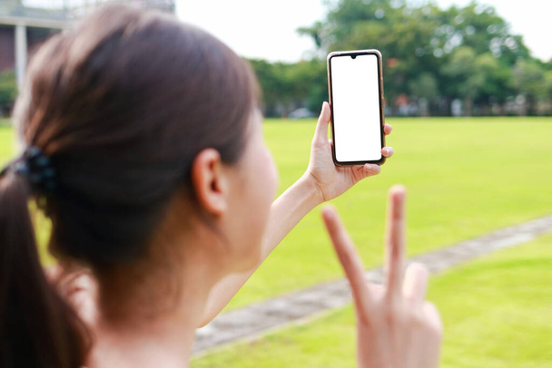Femme asiatique tenant smartphone en écran blanc Il peut être utilisé pour la publicité ou la présentation d'un produit. Concept de technologie de communication moderne. Médias sociaux. - Photo, image