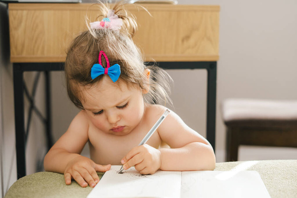 Καυκάσιο κοριτσάκι κάθεται στο σπίτι και ζωγραφίζει με μολύβι. Η έννοια της οικογένειας και της φιλίας. Το παιδί μαθαίνει ζωγραφίζοντας. Εκπαιδευτική έννοια - Φωτογραφία, εικόνα