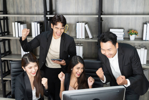 Les gens d'affaires heureux à l'ordinateur célèbrent le succès au travail assis dans le bureau moderne. Succès des négociations. équipe d'affaires regardant le moniteur d'ordinateur. - Photo, image