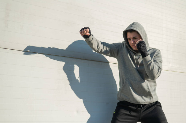 Caucasian man in hoodie is training boxing outdoors - Fotoğraf, Görsel