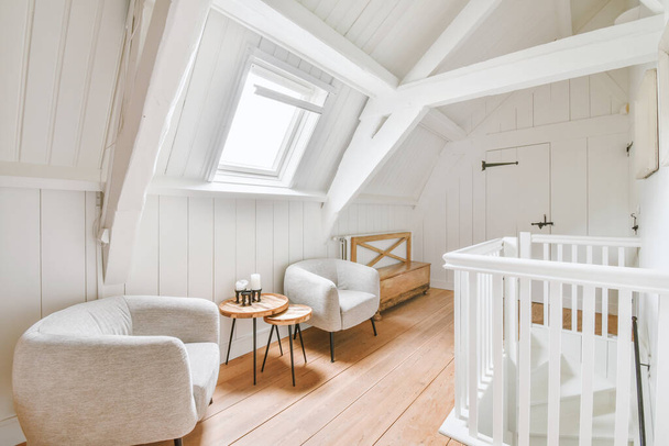 Interior of white room with baby crib and armchair near window with blue chest of drawers in daylight - 写真・画像