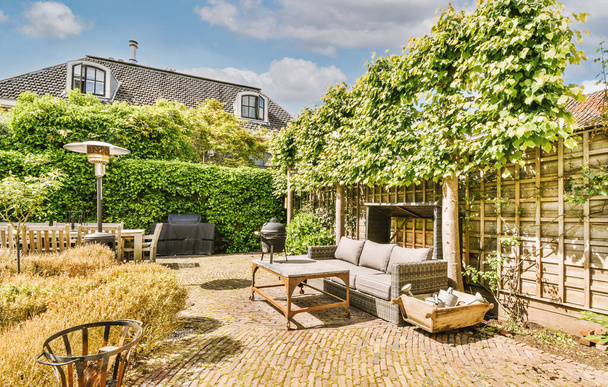 Neat paved patio with sitting area and small garden near wooden fence - Foto, afbeelding