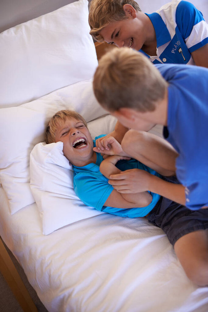 Having fun. A little boy play fighting with his brothers on the bed - Photo, Image