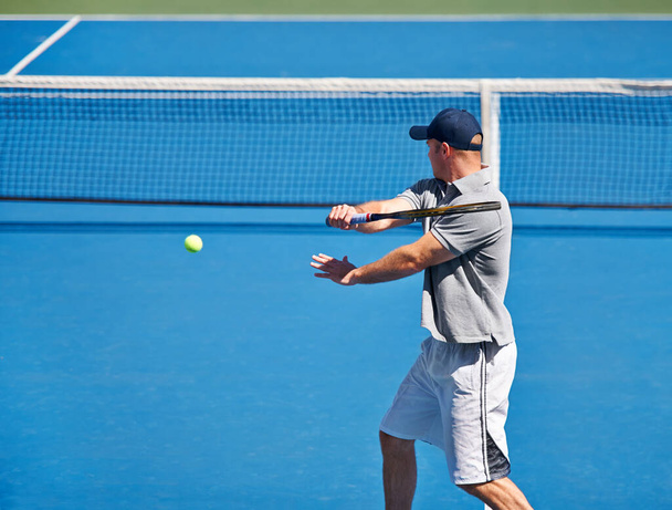 Прийти на каждую тренировку по теннису. мужчина пытается вернуть мяч на теннисный корт - Фото, изображение