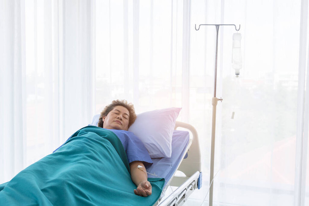 Eine alte Dame liegt auf einem Krankenhausbett. - Foto, Bild
