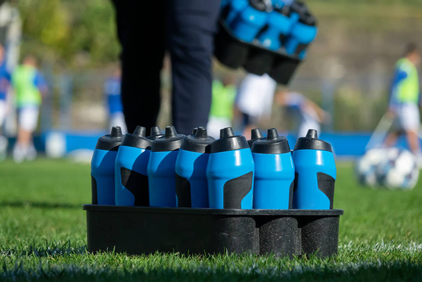 Butelki sportowe ze słodką wodą lub napojem energetycznym na boisku piłkarskim - Zdjęcie, obraz