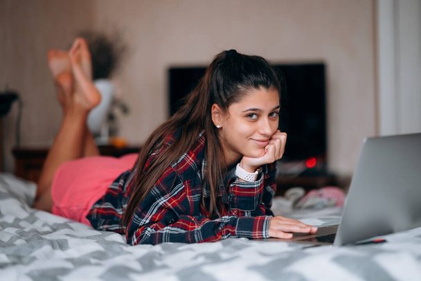 Вибірковий фокус молодої жінки працює під час роботи з ноутбуком, що лежить на ліжку
 - Фото, зображення