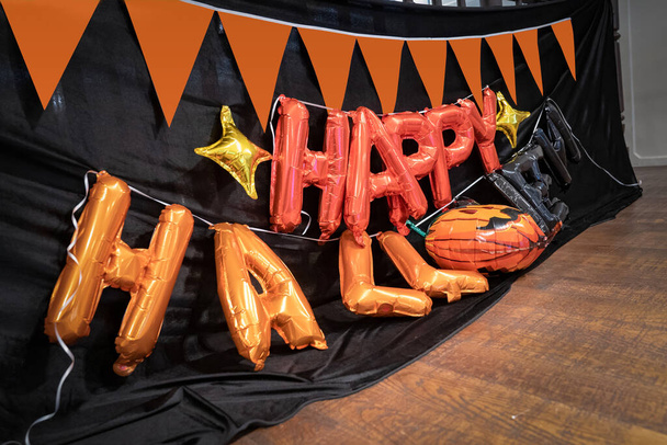 Cadılar bayramı turuncu balon mektupları 2. katta balkabağı bayrağı ve cadılar bayramı partisinde siyah bez arkaplanlı terasa asılmak için hazırlanır..   - Fotoğraf, Görsel