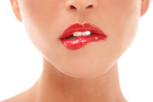 Ízletes ajkak. Egy fiatal nő, aki vörös rúzzsal harapdálja az ajkát - kivágták. - Fotó, kép