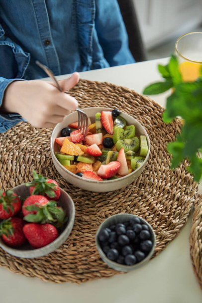 Healthy food at home. Cute little girl eats fruit salad  - Фото, зображення