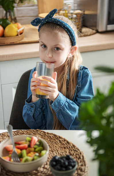 Aliments sains à la maison. Petite fille mignonne mange de la salade de fruits  - Photo, image