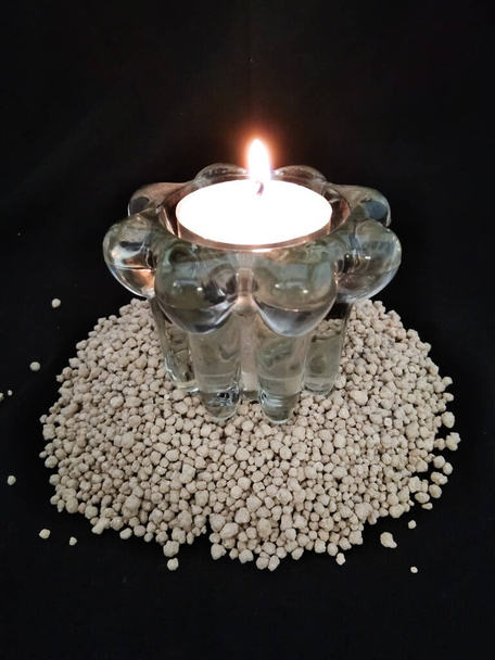 Kirkkaasta lasista valmistettu kynttilänjalka, jossa palava kynttilä mustalla pohjalla - Valokuva, kuva