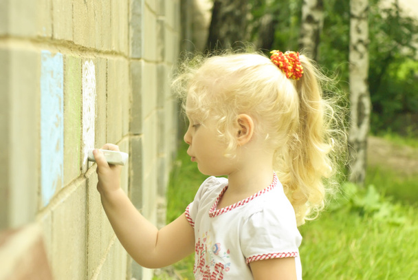 Little girl drawing with chalk on the wall - Photo, Image