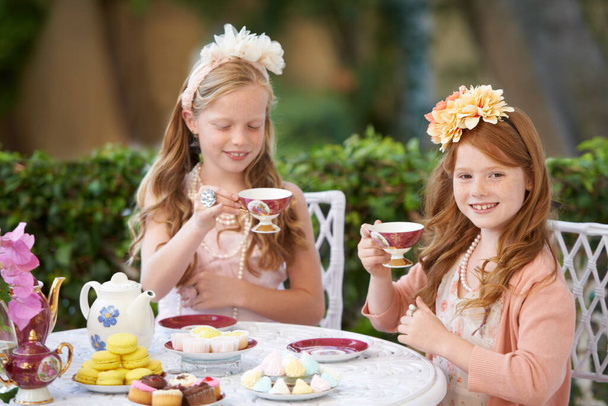 Haciendo una fiesta de té imaginaria. Dos chicas jóvenes haciendo una fiesta de té en el patio trasero - Foto, Imagen