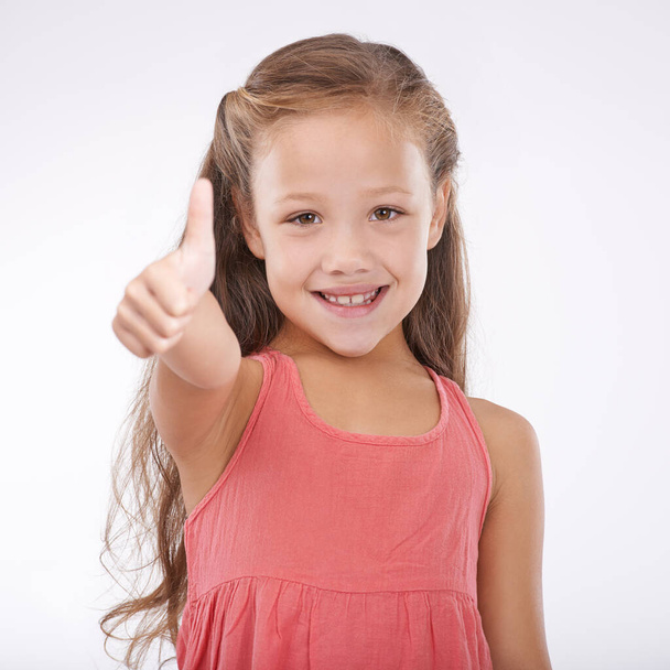 Shes so happy and carefree. Studio portrait of a cute young girl giving a thumbs-up to the camera - Fotó, kép