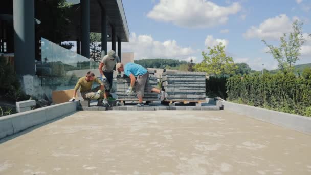 Colocando losas de pavimentación. Los hombres maestros hacen un camino de adoquines - Metraje, vídeo