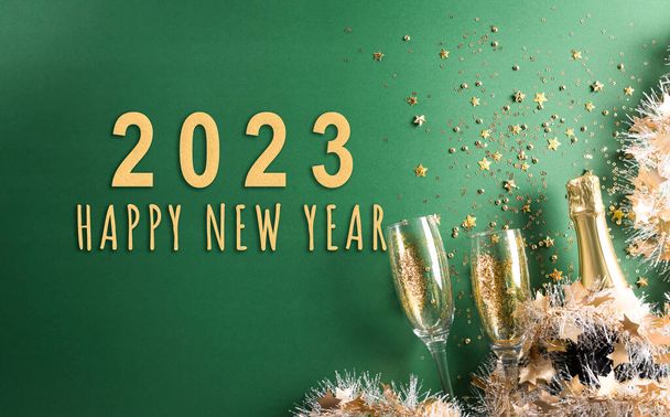 Gelukkig Nieuwjaar viering achtergrond concept. Champagne met glas, gouden lint, sterren en kerstbal op groene achtergrond. - Foto, afbeelding