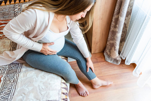 Leg pain pregnant woman. Pregnancy girl have leg disease, ankle pain doing health massage exercise. Foot swelling during pregnancy - Fotó, kép