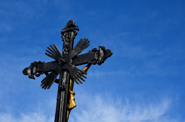 Réparer les tortures de Dieu à la campagne. la croix en métal est peinte et dorée. les environs sont aménagés et complétés par un banc fait d'un râteau de bois dans la prairie. chêne, grès - Photo, image
