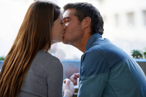 New love knows no boundries. a young couple kissing in a cafe - Foto, Imagem