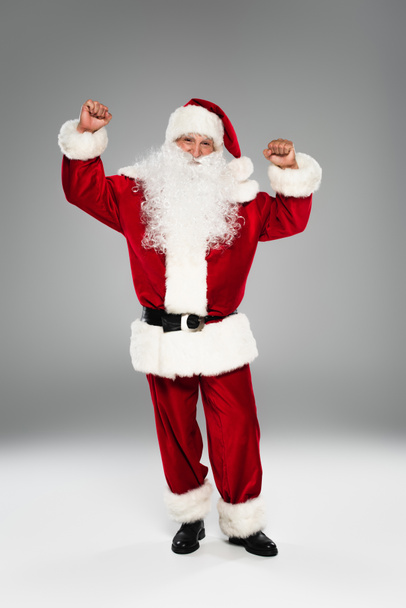 Emocionado Santa Claus mostrando sí gesto sobre fondo gris  - Foto, Imagen