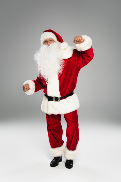 Pełna długość barded Santa Claus taniec i patrząc w kamerę na szarym tle  - Zdjęcie, obraz