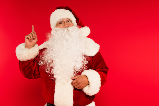 Bearded santa claus in eyeglasses having idea on red background  - Foto, Bild