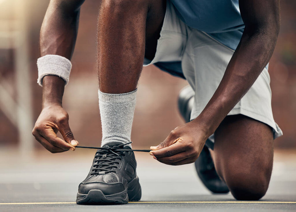 Fitness, running and shoes of black man for training for sports, motivation and start of workout. Exercise, health and wellness with runner fixing his laces in road for cardio, energy and performance. - Photo, image