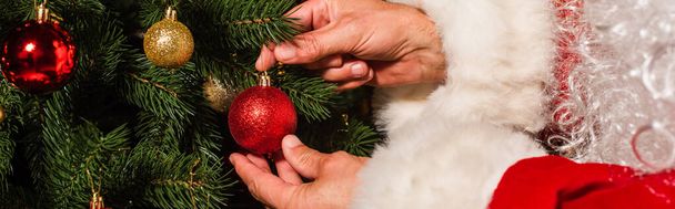 Vista cortada de Papai Noel barbudo decorando árvore de Natal com bugigangas, banner  - Foto, Imagem