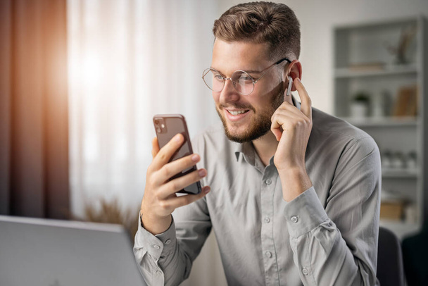 Handsome bearded student listening to online course, happy smiling man use earphones to studying, ebook concept - Photo, Image