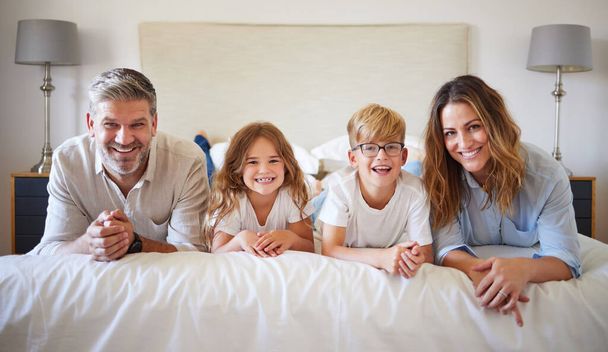 Отдых, семейный и постельный портрет со счастливыми родителями маленьких детей в уютном канадском доме отдыха. Любовь, забота и поддержка мамы и папы, наслаждающихся приятным времяпрепровождением с маленькими детьми в спальне - Фото, изображение
