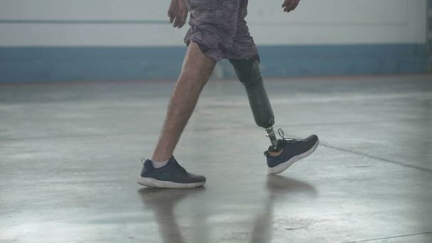 Disabled person walking with his prosthetic leg indoors. Amputee man walks with prosthetic leg - Foto, afbeelding