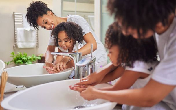 Anya és gyermek a fürdőszobában kezet mos, takarít és tanul higiéniát otthon. Fiatal anya lány tanítás és segít neki, hogy mosson kezet szappannal és vízzel a gyermek fejlődését az egészségügyben. - Fotó, kép