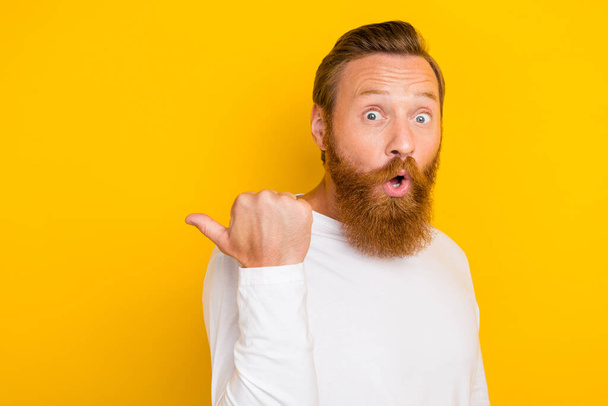 Photo portrait of nice young guy finger point copyspace impressed sales dressed trendy white look isolated on yellow color background. - Photo, image