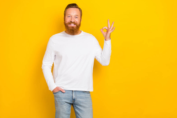 Photo of young handsome smiling redhair guy beard showing okey symbol recommend nice app for work isolated on yellow color background. - Photo, image