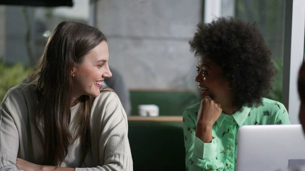 会話の中でコーヒーショップで多様な女性。彼女の3つのグループは、ノートパソコンの笑いとカフェの場所で座って話す - 写真・画像