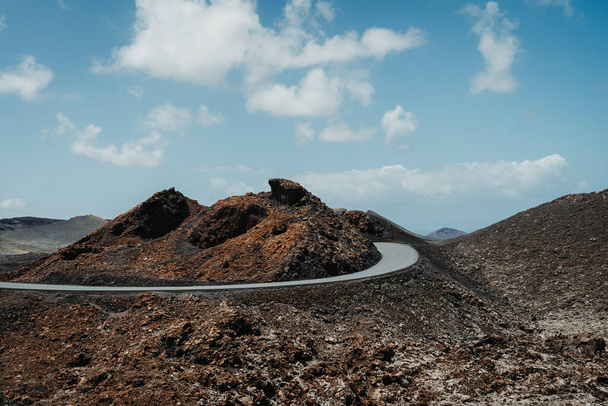 Strada asfaltata nel paesaggio vulcanico arido del Parco Nazionale di Timanfaya, Lanzarote, Isole Canarie, Spagna - Foto, immagini