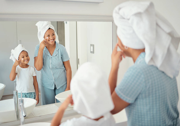 Mother and girl doing skincare in the morning in the bathroom together. Black family in their home doing skincare routine, using products and lotion on their face. Family, face cream and facial care. - Foto, Bild