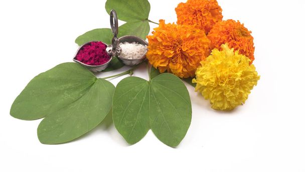green leaves with marigold flowers, arranged with rice and kumkum on white background - 写真・画像