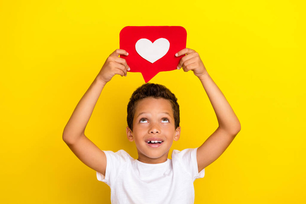 Photo of impressed small boy look heart wear white t-shirt isolated on yellow color background. - Foto, afbeelding