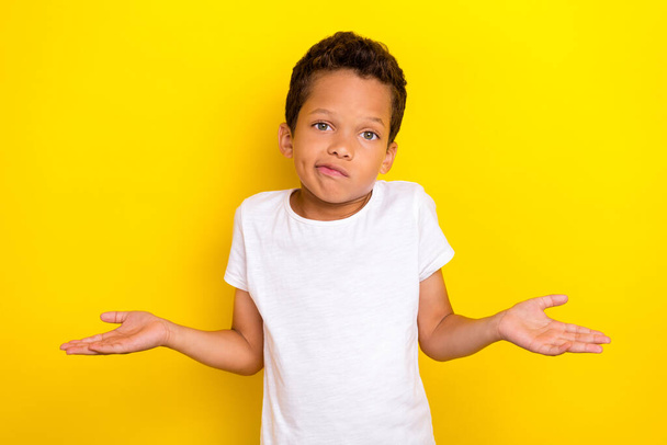 Photo of cute stylish boy arm shoulder raise dont know question oops sorry look empty space isolated on yellow color background. - Foto, immagini