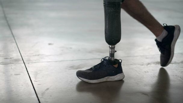 Osoba niepełnosprawna chodząca z protezą nogi w środku. Amputee człowiek idzie z protezą nogi - Zdjęcie, obraz