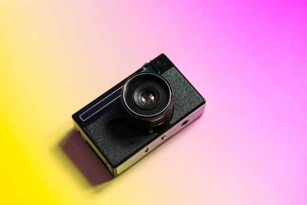 Fotocamera a pellicola vintage su uno sfondo minimale a colori. Fotografia, stile di vita hipster. Foto di alta qualità - Foto, immagini