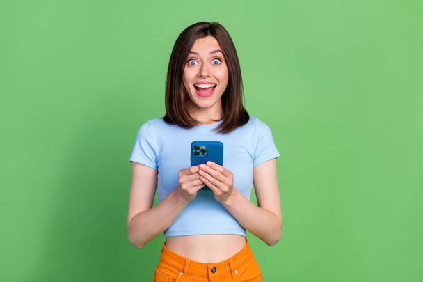 Photo of shocked funny girl hold telephone open mouth unbelievable isolated on green color background. - Fotografie, Obrázek