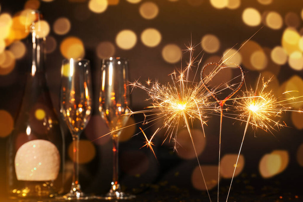 Beautiful Christmas sparklers, glasses and bottle of champagne on dark background - Φωτογραφία, εικόνα