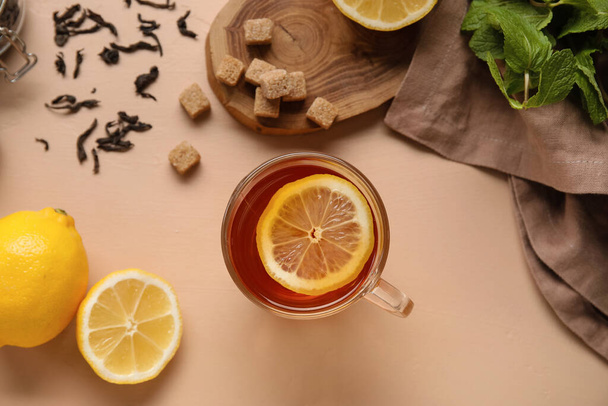 Copa de vidrio de té negro con limón sobre fondo beige, primer plano - Foto, imagen