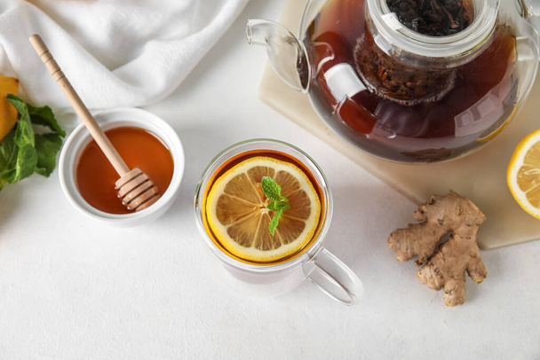 Glass cup of black tea with lemon, mint, honey and ginger on white background - Valokuva, kuva