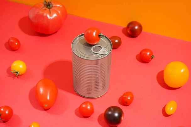 lata de lata y diferentes tomates frescos sobre fondo de color - Foto, imagen